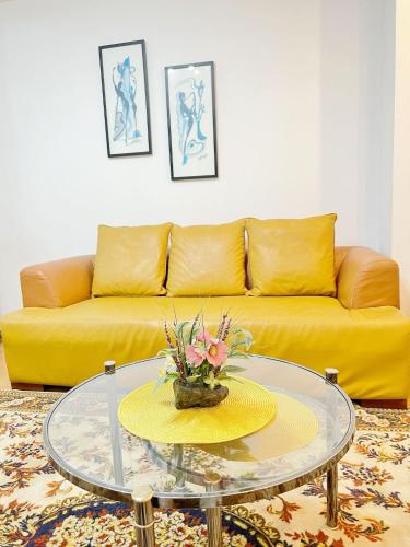 a living room with a yellow couch and a glass table at Home NP Apartments in Novi Pazar