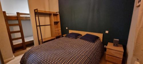 a bedroom with a bed with two blue pillows at Appartement neuf et confortable dans le Haut Jura in Lac des Rouges Truites