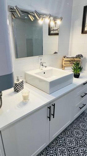 a white bathroom with a sink and a mirror at Casa da Marina in Angra do Heroísmo