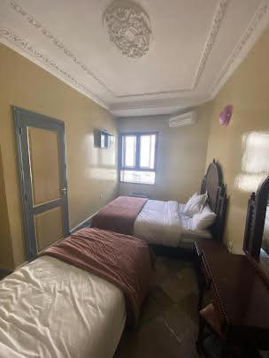 a bedroom with two beds and a window at HOTEL AL MAMOUN in Casablanca