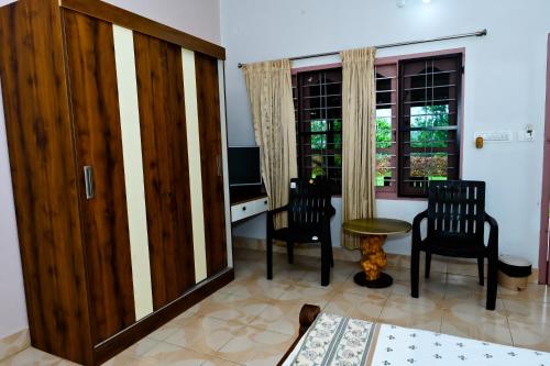 a room with two chairs and a desk with a television at Prakruthi Home Stay in Sollebail
