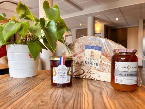 two jars of jam on a wooden table with a plant at Brit Hotel Confort Montauban in Montauban