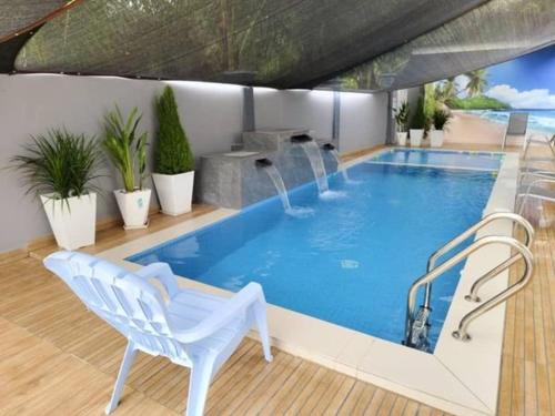 - une grande piscine avec une chaise blanche dans l'établissement NASUHA HOMESTAY 1 TEMERLOH Semi-D House, 2 Bedroom, 3 Bathroom, 3 Unit Aircond, Free Wifi and Netflix, Near Hospital with Private Pool, à Temerloh