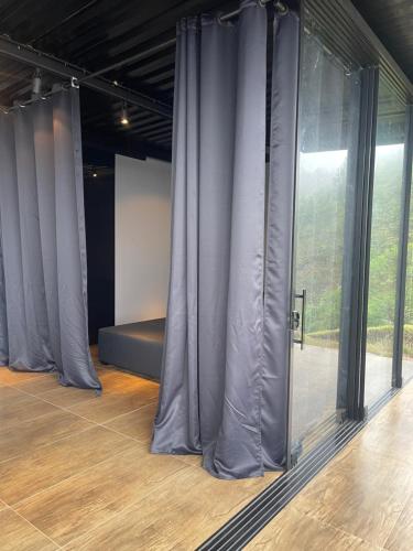a room with gray curtains and a bed in front of a window at Casa Vilas Boas Macacos in Nova Lima