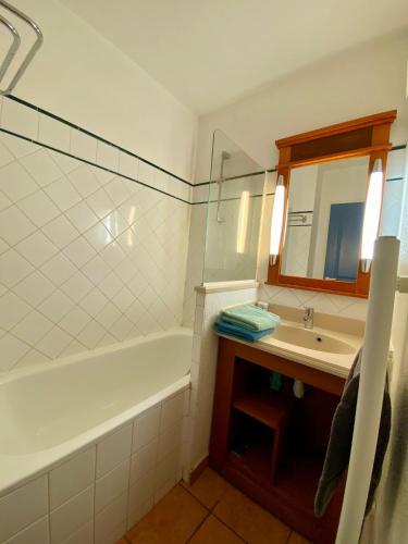 une salle de bain avec une baignoire, un lavabo et un miroir dans l'établissement AGREABLE T2 LISIERE DU GOLF LACANAU OCEAN, à Lacanau-Océan