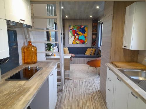 a kitchen with white cabinets and a couch in the background at Tiny House Egmond in Egmond aan den Hoef