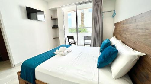 a bedroom with a bed with blue and white pillows at Hotel Chayrama in Santa Marta