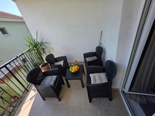 a balcony with three chairs and a table with a plant at Apartmani Komatina Đenovići 2 in Herceg-Novi