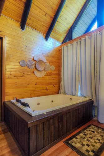 a bath tub in a room with a wooden wall at Cabanas Capoeiras in Urubici