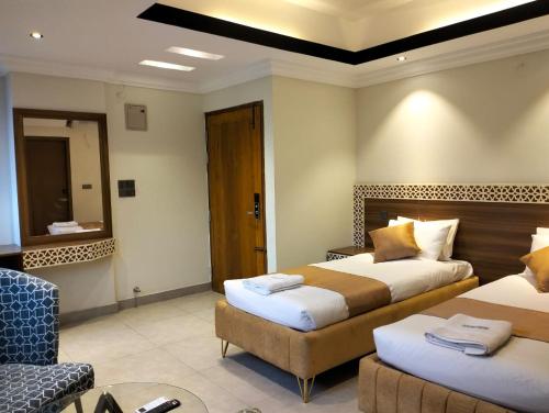 a hotel room with two beds and a chair at Hotel Centro Residential in Chittagong