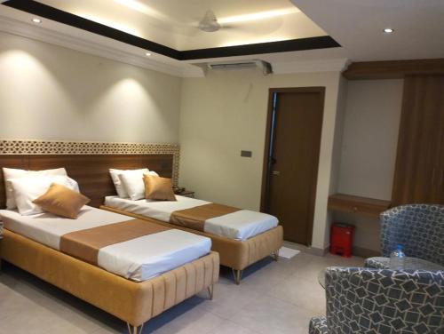 a hotel room with two beds and a chair at Hotel Centro Residential in Chittagong
