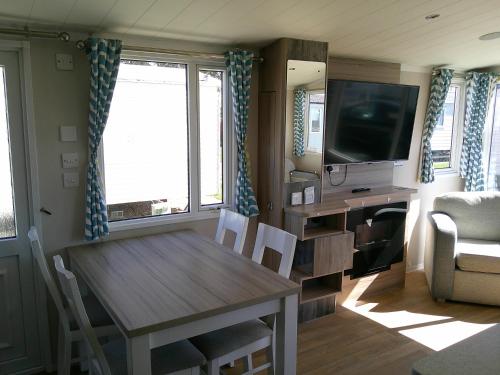 a living room with a table and a tv at Kingfisher Surf Shack 8 Berth Central Heated Close to site entrance FREE WIFI in Ingoldmells