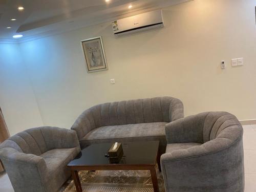 a living room with two chairs and a table at Hona Al Holm Furnished Units in Dammam