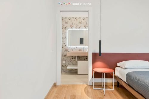 a bedroom with a bed and a mirror and a stool at Le Dimore dei Fiori, Terre Marine in La Spezia