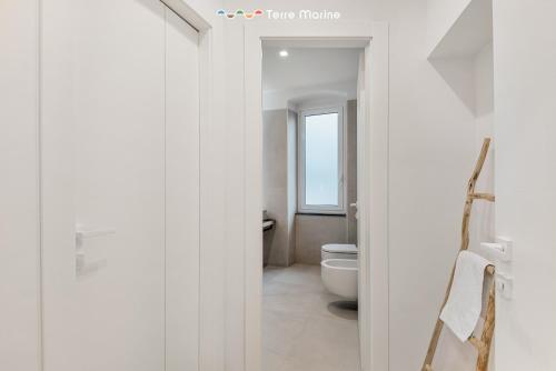 a white bathroom with a toilet and a window at Le Dimore dei Fiori, Terre Marine in La Spezia