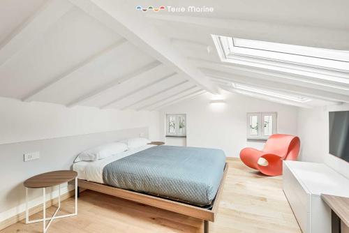 a white bedroom with a bed and a red chair at Le Dimore dei Fiori, Terre Marine in La Spezia