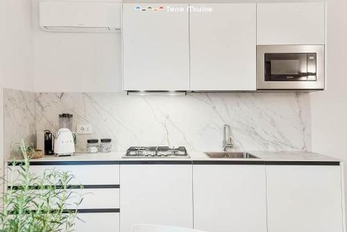 a white kitchen with a sink and a microwave at Le Dimore dei Fiori, Terre Marine in La Spezia
