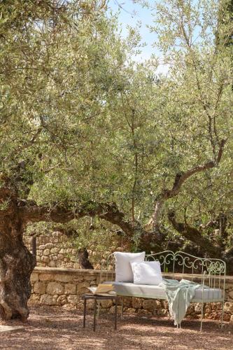 a bench with pillows sitting under a tree at Liodentra in Kardamili