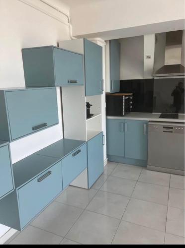 une cuisine avec des armoires et des appareils bleus et blancs dans l'établissement appartement meuble vue sur le port, à Canet