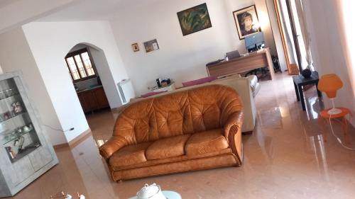 a leather couch in a living room with a piano at TUSCIA RELAx MARE in Civitavecchia