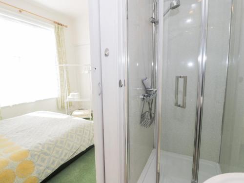 a bathroom with a shower next to a bed at Seawinds in Colwyn Bay