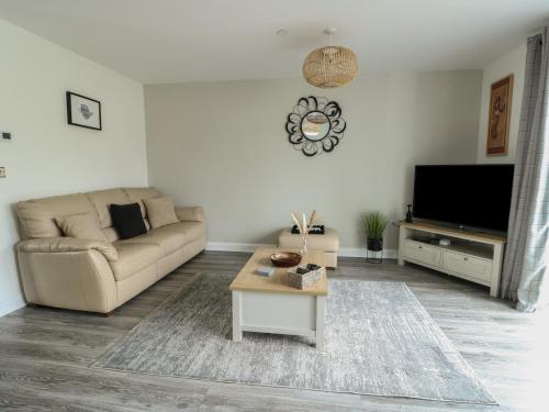 a living room with a couch and a tv at 4 Parc Delfryn in Llanallgo
