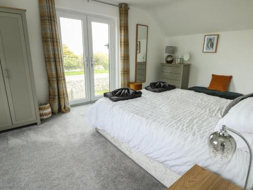 a bedroom with a large white bed and a window at 4 Parc Delfryn in Llanallgo