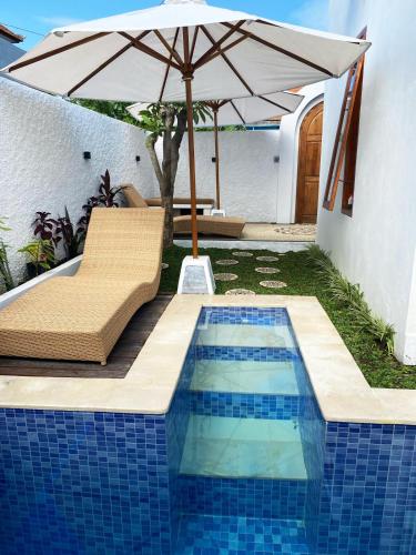 a pool with an umbrella and a chair and a table at Villa Katak Singaraja in Babakan Sangsit