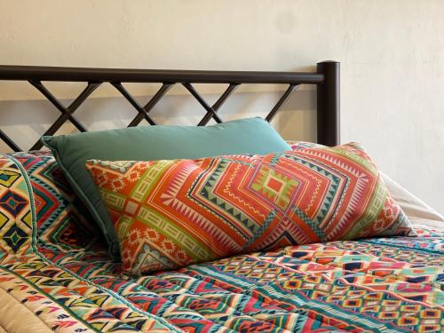 a bed with colorful pillows on top of it at Casa Mar y Sierra in Oaxaca City