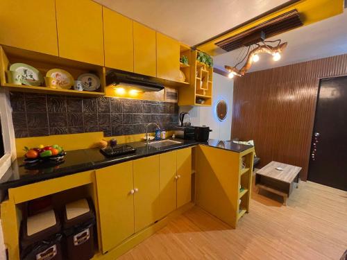 a small kitchen with yellow cabinets and a sink at Golden Poppy Cozy Condo in Cebu City