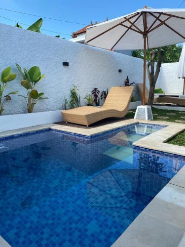 a swimming pool with a chair and an umbrella at Villa Katak Singaraja in Babakan Sangsit
