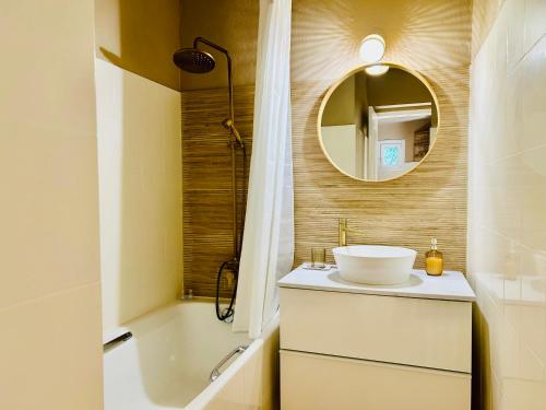 une salle de bain avec un lavabo, une baignoire et un miroir dans l'établissement Charmant et cosy T2 à deux pas du port dans un quartier calme, à Cavalaire-sur-Mer