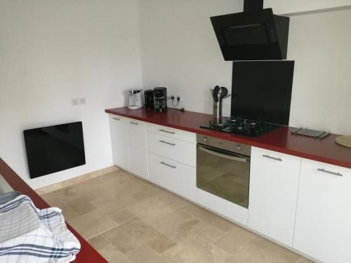 a kitchen with white cabinets and a red counter top at Le Petit Moineau in Arthon