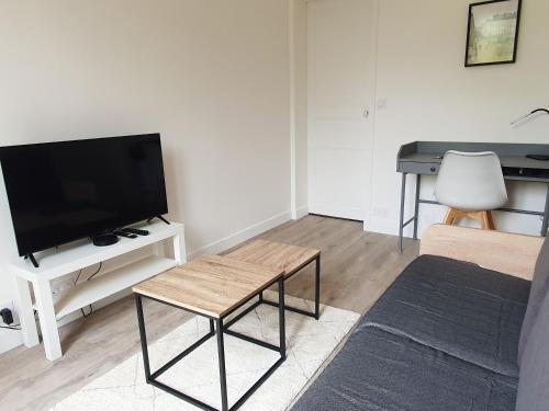 - un salon avec une télévision et un bureau dans l'établissement Joli studio en centre-ville à 20 min de Paris, à Vélizy-Villacoublay