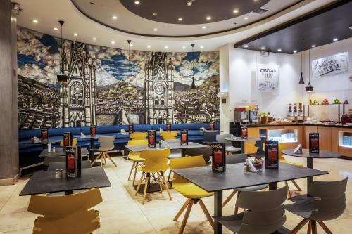 a restaurant with tables and chairs and a mural at ibis Quito in Quito