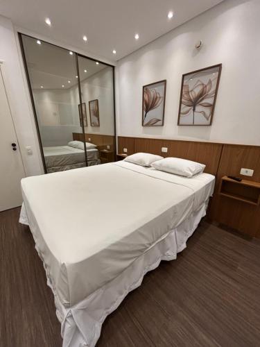 a large white bed in a room with a mirror at Summit Flat Exclusivo Proximo ao center Vale shopping in São José dos Campos