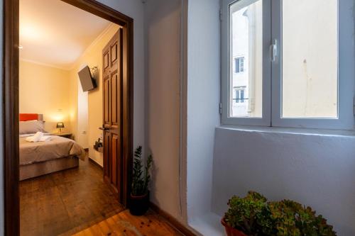 a hallway with a window and a bed in a room at Tiny magic studio in Corfu