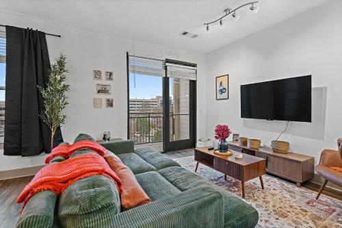a living room with a green couch and a flat screen tv at Mid-Century Charm in Midtown Nashville in Nashville