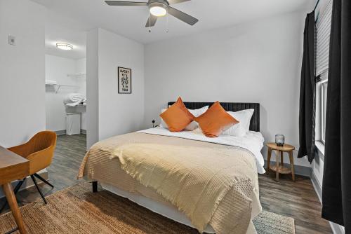 a bedroom with a bed with orange pillows and a ceiling fan at Mid-Century Charm in Midtown Nashville in Nashville