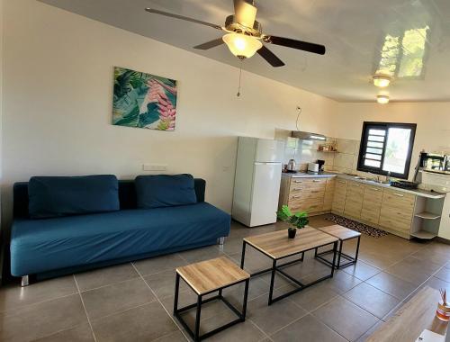 a living room with a blue couch and a kitchen at Teahupo'o Lodge - accès mer et vue montagne - canoes gratuits in Vaihi