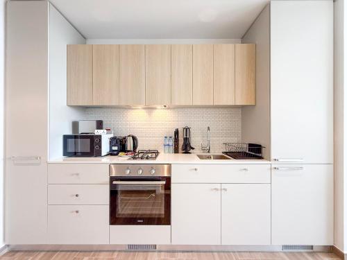 a kitchen with white cabinets and a stove top oven at Modern Chic Studio Apartment, Belgravia Heights 2, JVC Dubai in Dubai