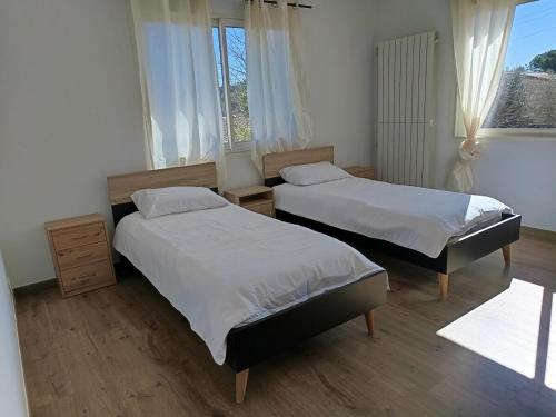 deux lits dans une chambre avec deux fenêtres dans l'établissement Appartement T4 à l'étage d'une villa avec piscine et jardin, à Grasse
