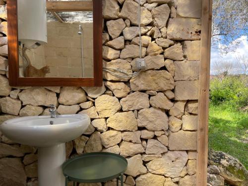 ein Badezimmer mit einem Waschbecken und einer Steinmauer in der Unterkunft Ananda Glamping natural escape in Palazzolo Acreide