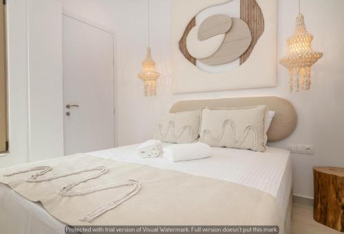 a bedroom with a bed with white sheets and chandeliers at Joyful Tinos in Tinos Town