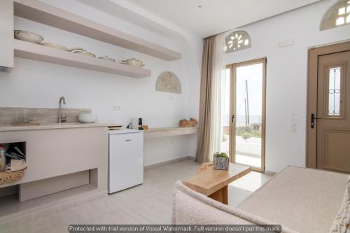 a kitchen and living room with white walls and a table at Joyful Tinos in Tinos Town