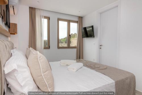 a bedroom with a bed with white sheets and two pillows at Joyful Tinos in Tinos Town