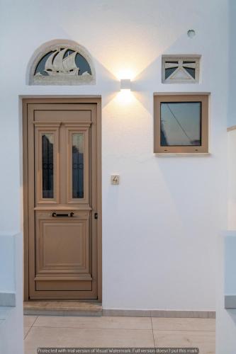 a wooden door in a white wall with a window at Joyful Tinos in Tinos Town