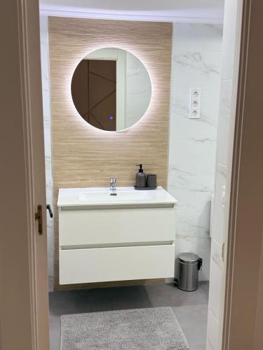 Un baño con un lavabo blanco y un espejo. en Ámplio piso en el corazón de Torremolinos, en Torremolinos