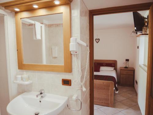 a bathroom with a sink and a mirror and a bed at La Majon de Fohten in Montjovet