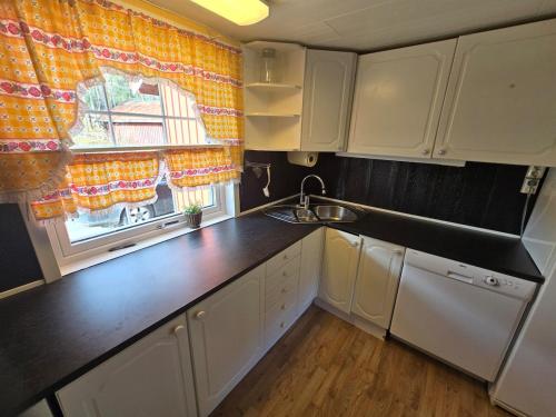 a kitchen with white cabinets and a sink and a window at Rent your own home in Velfjord in Saus